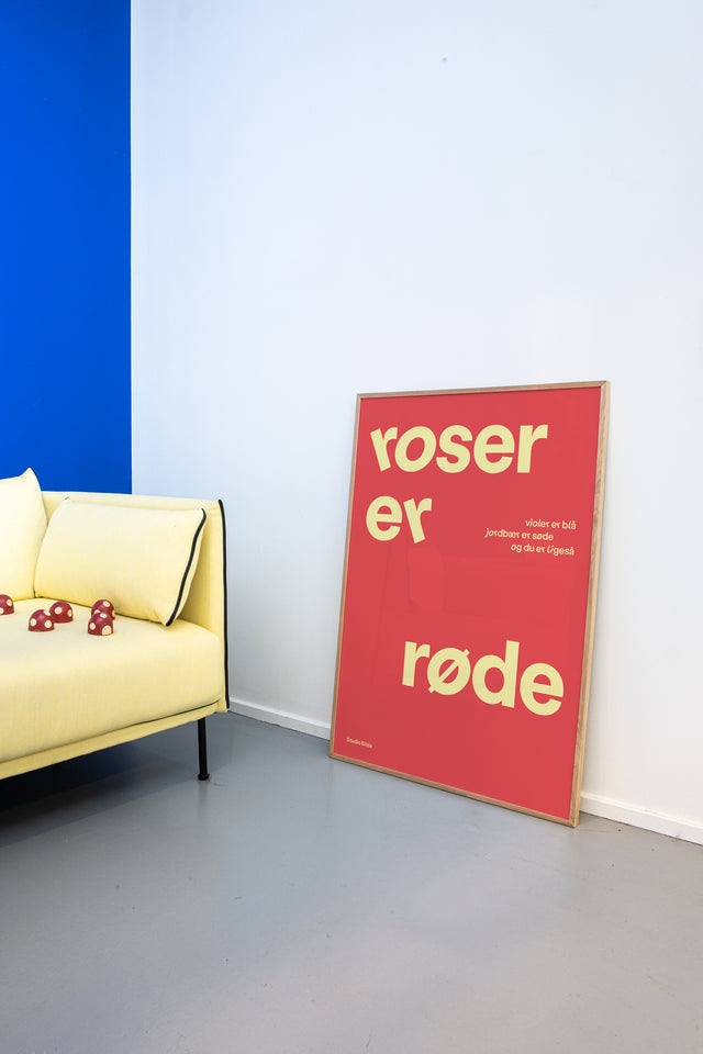 Rød "roser er røde" børneplakat på børneværelse med gul sofa og blå farvevæg