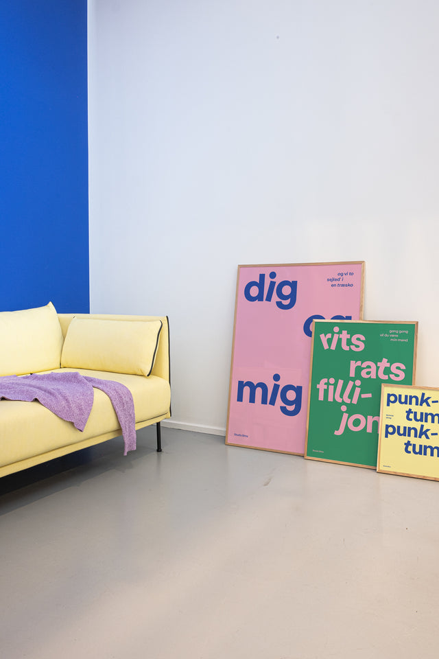 Lyserød, grøn og gul børneplakater på børneværelse med gul sofa og blå farvevæg